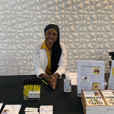 Sis. Angeline X of Muhammad Mosque 102 in Chester, Pa sitting at table.
